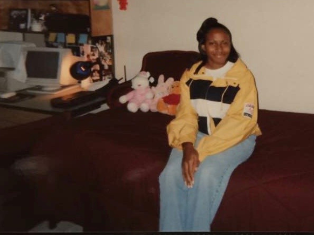 young college student sitting in dorm room on bed