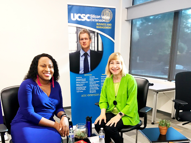 two women sitting smiling one is wearing a purple dress the other lime green