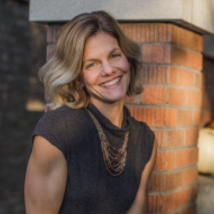 Headshot of a female financial advisor sitting outside next to a brick column