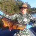 financial advisor on a boat wearing camouflage a hat and sunglasses holding a fish.