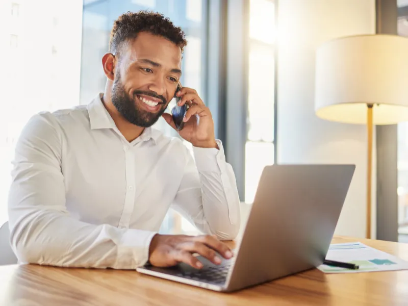 financial advisor talking on the phone searching Business Coaching for financial advisors on the computer