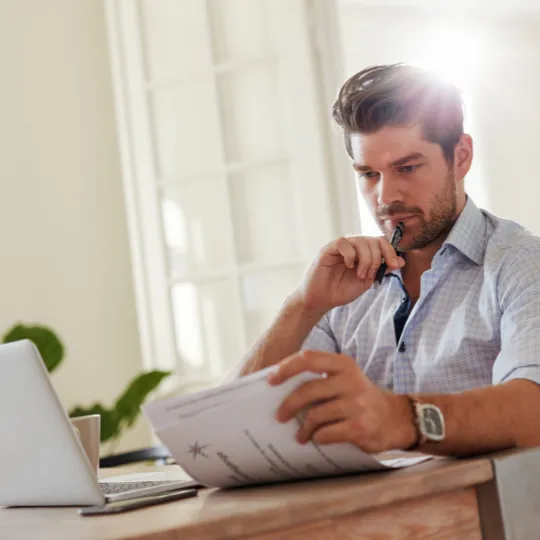 man at desk reading operational procedures from a business coaching program
